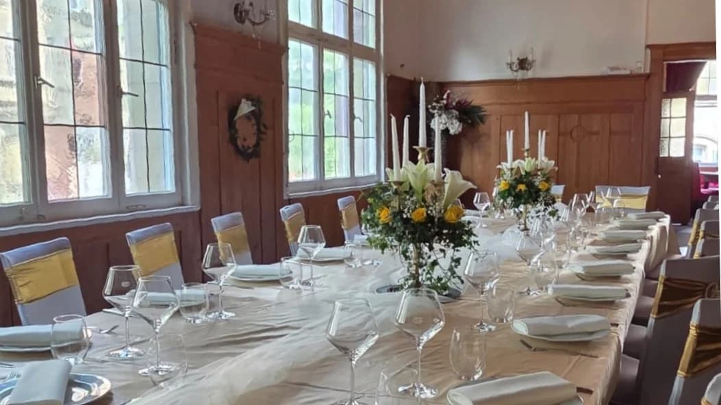 Festlich gedeckte lange Tafel im historischen Goldoni-Saal mit Bogenfenstern, goldenen Stuhlhussen und Tischdeko aus weißen Lilien und gelben Rosen