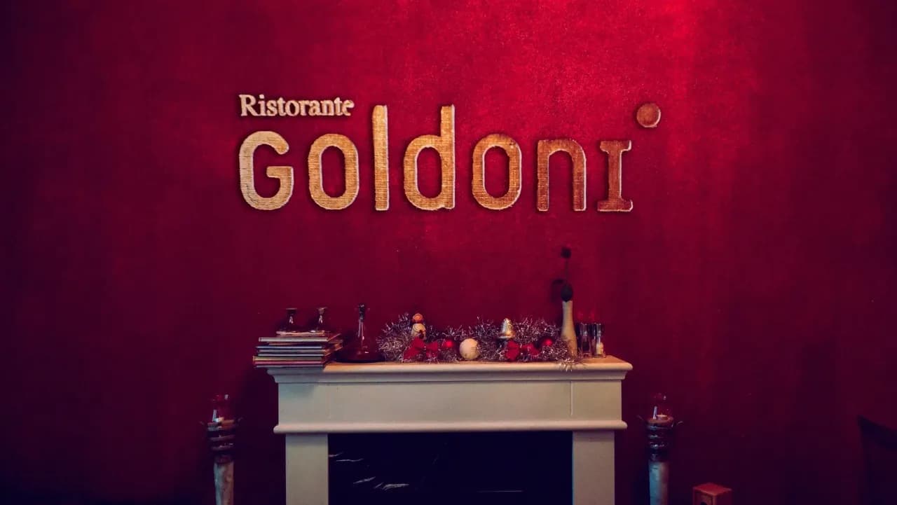 Ristorante Goldoni — Wandschild im Innenraum, gold auf rotem Samt